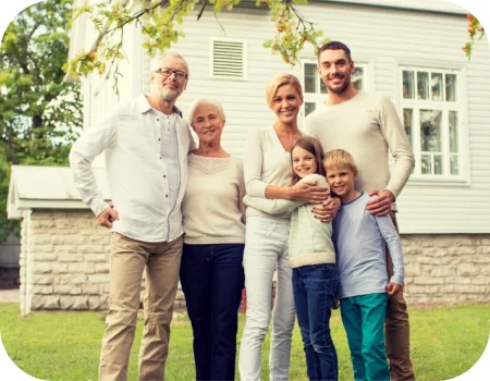 Happy parent, grandparents, and children standing in front of their home