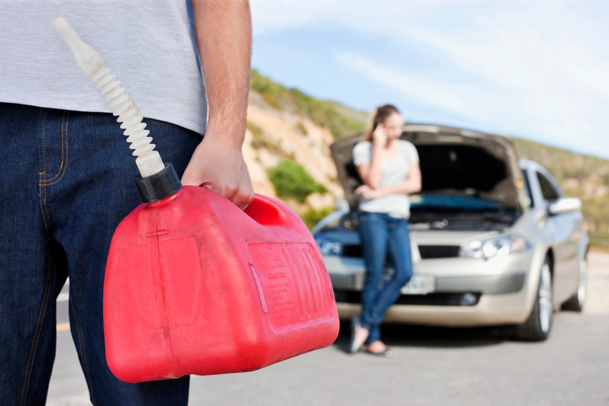 young man is holding a gas can while a woman talks on a cell phone by the car roadside assistance