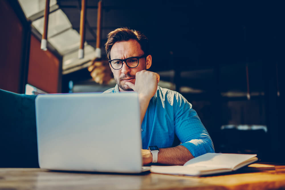 worried business man in front of laptop business disruption coronavirus