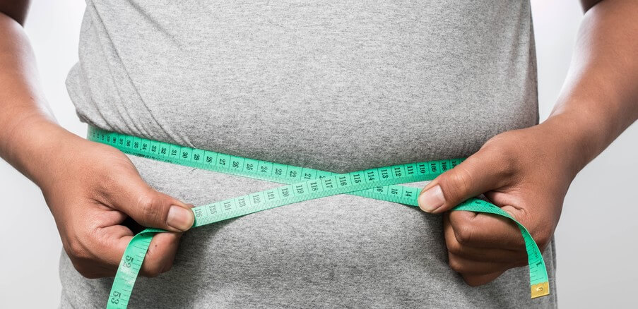 how_does_insurance_for_obese_people_work man measuring his stomach with green measuring tape