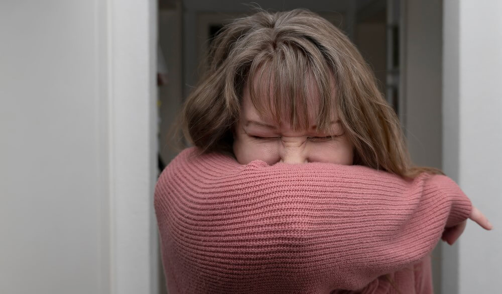 woman practices sneezing etiquette to protect yourself against coronavirus