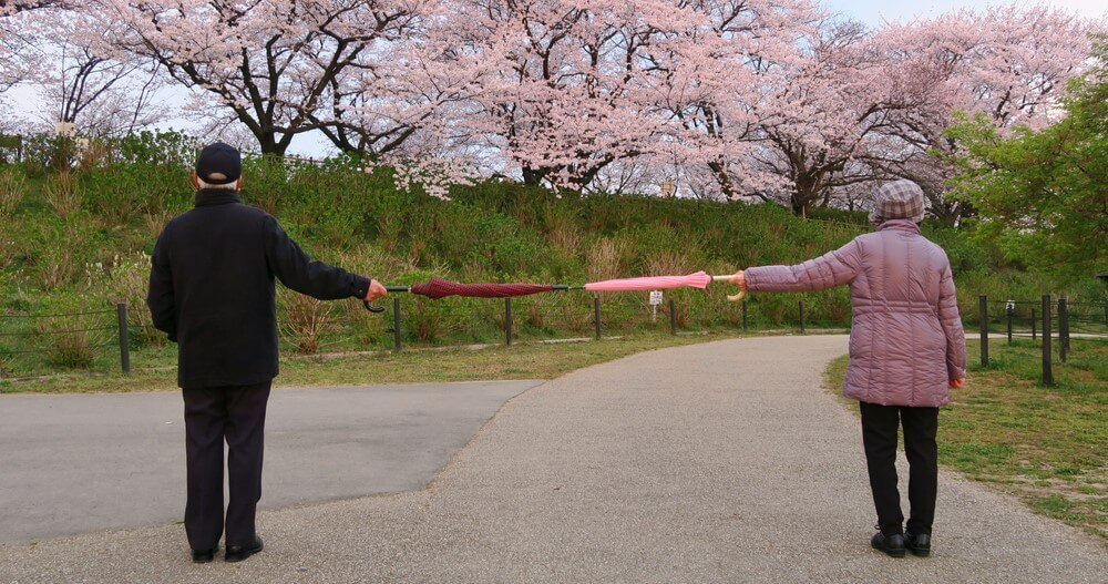 couple social distancing in park with umbrella prevent coronavirus