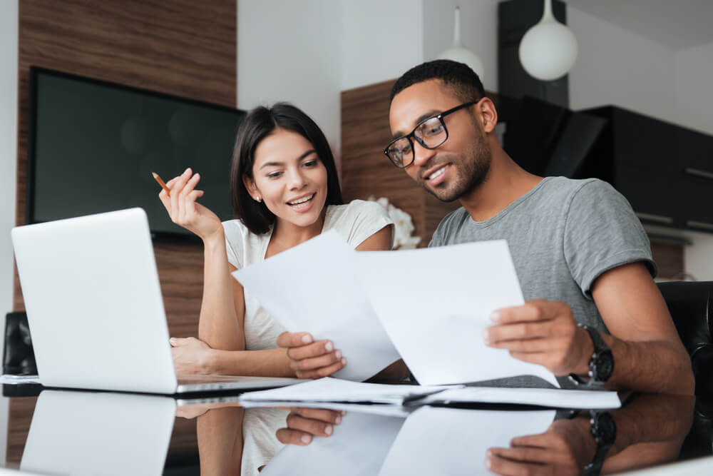 young couple checking their business finances on laptop with bond insurance