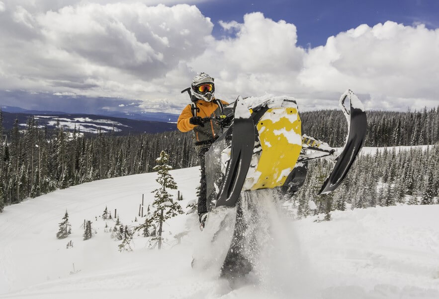 man on snowmobile jumping on a snowy mountain