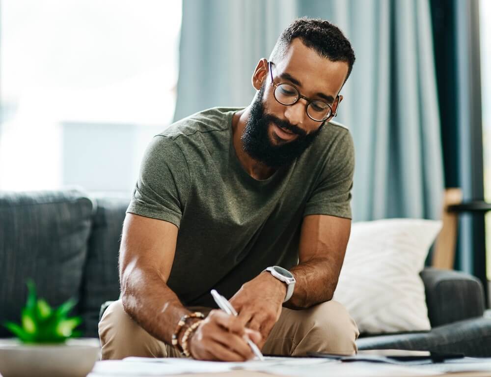 african american man writing on paper while buying homeowners insurance