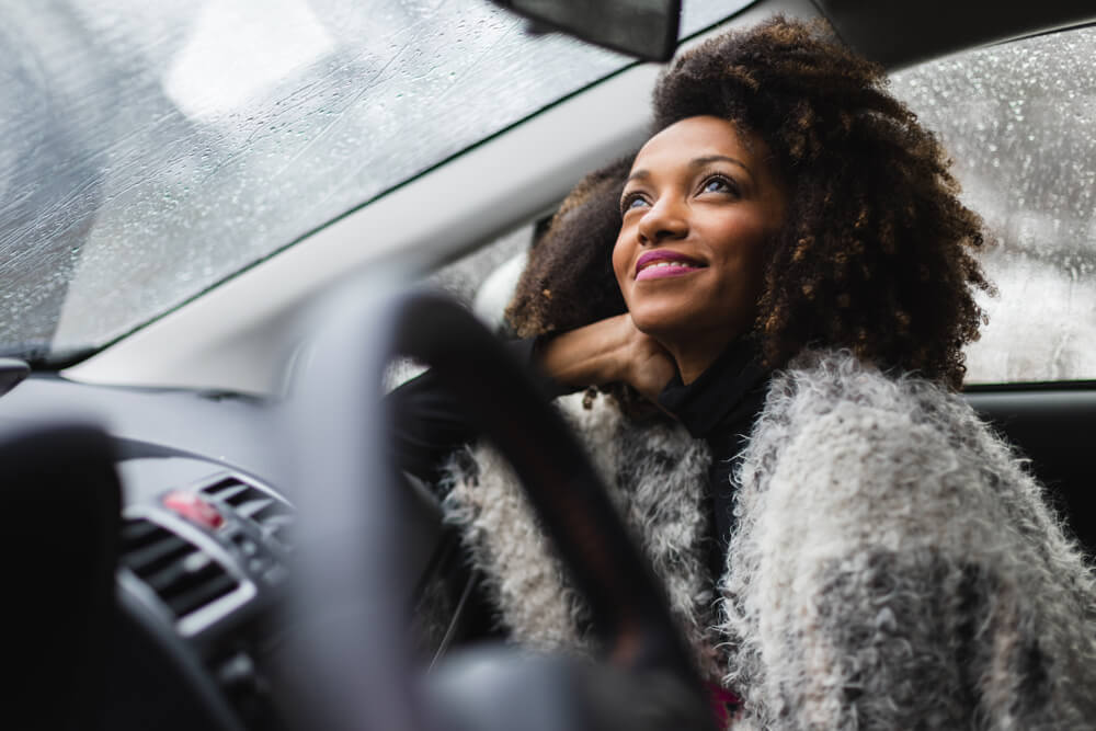 woman looking out a car window happy during a holiday road trip