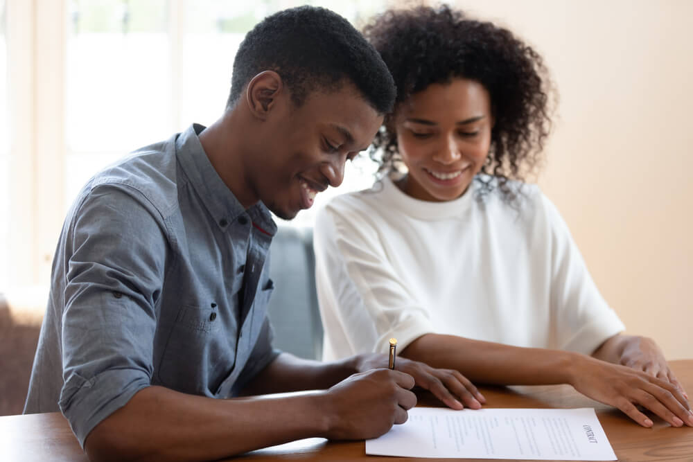 african american couple happy signing their life insurance policy