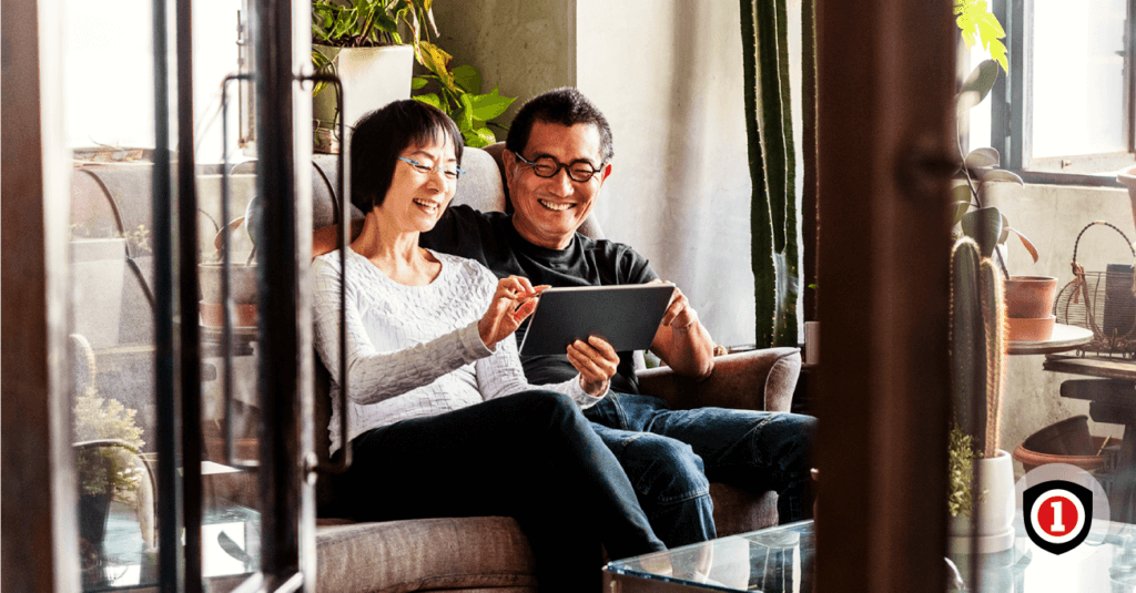 Asian couple smiling in their living room while they covered by home insurance