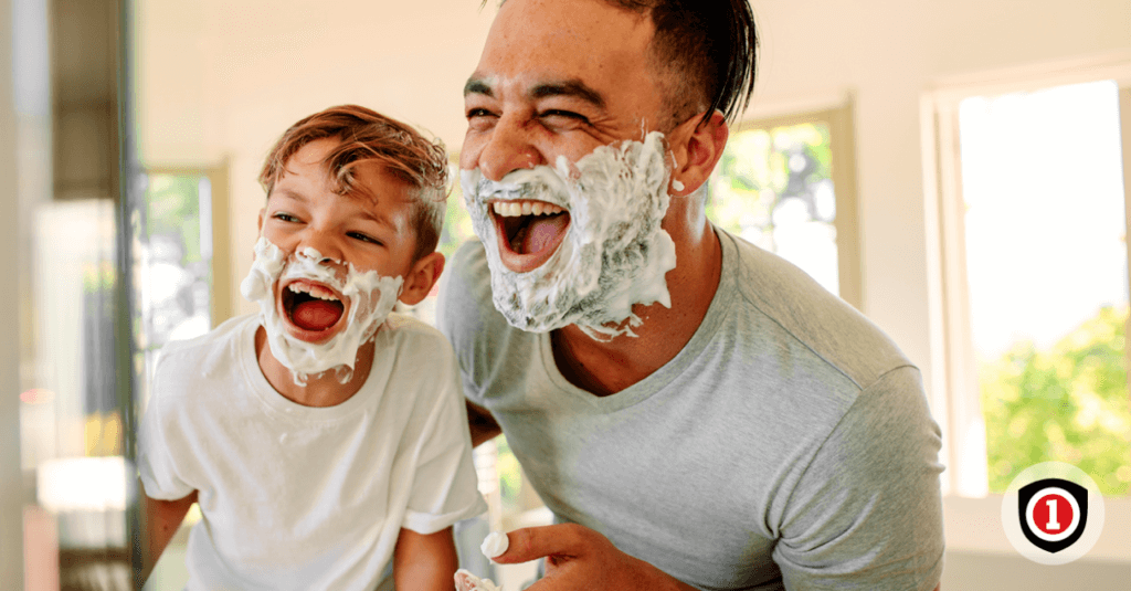 Father and son smiling while they are playing to shave