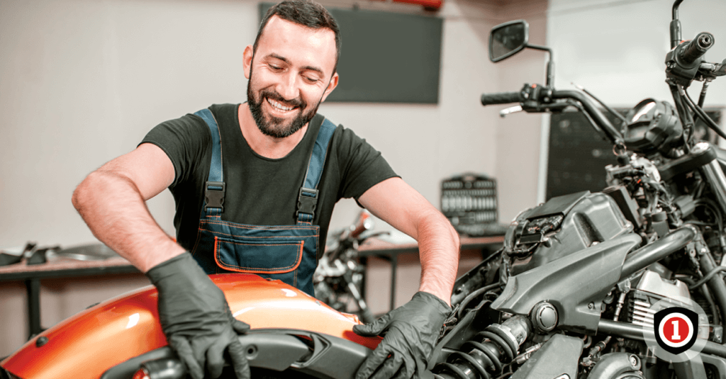 A man smiling while fixing his motorcycle 