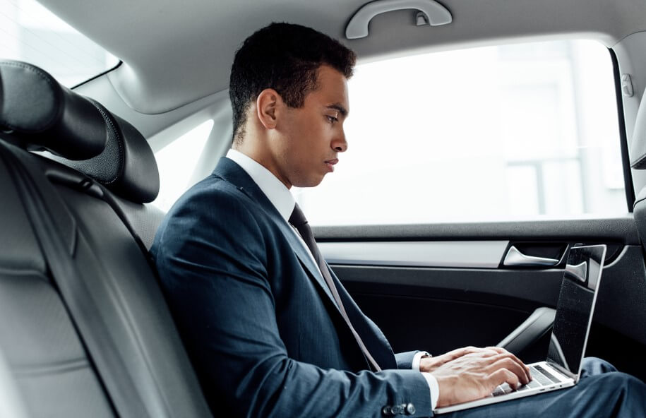 side view of african american businessman using laptop in car with insurance