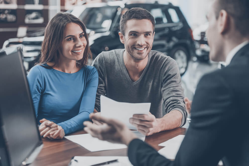 happy couple buying a new car with insurance