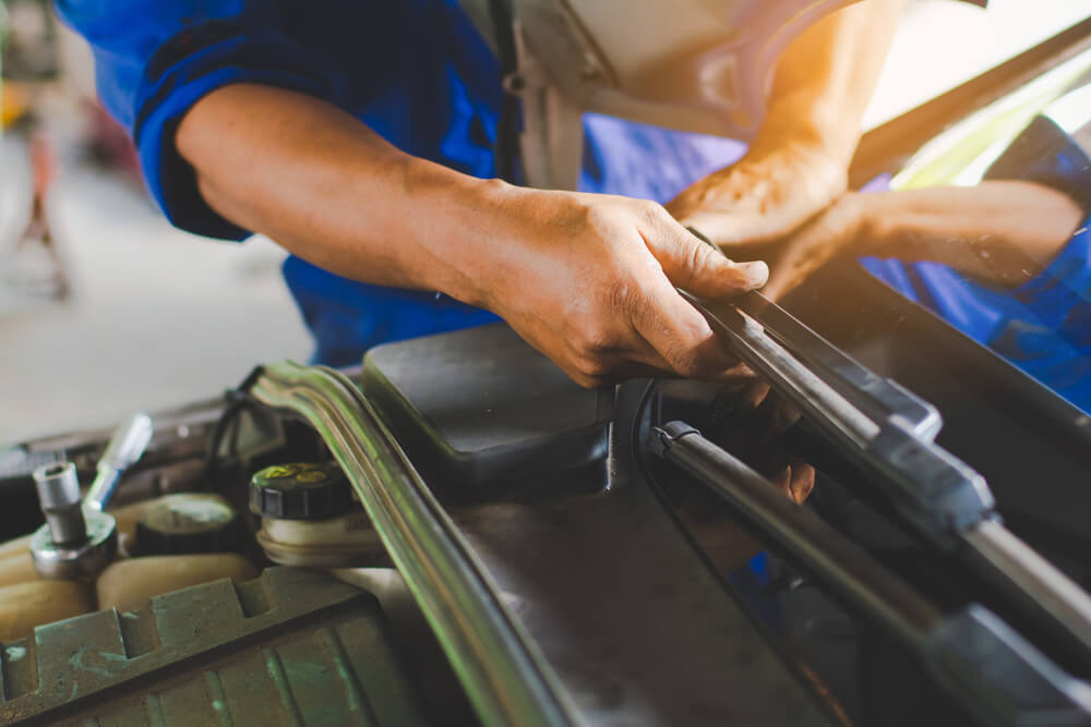 Technician changing windscreen wipers on a car