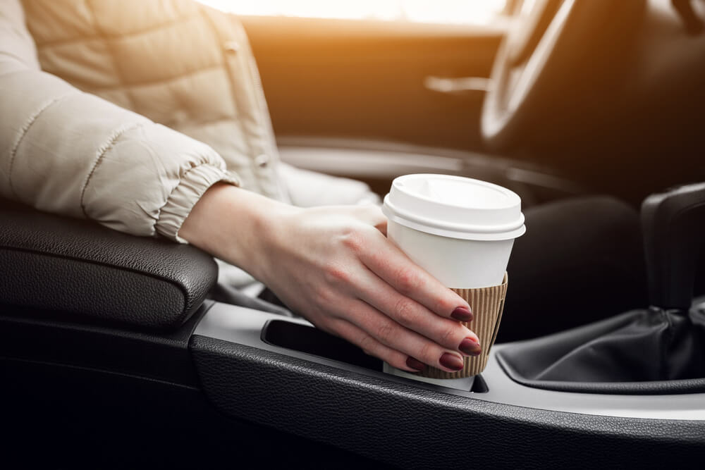 woman holding coffee cup on car holder 