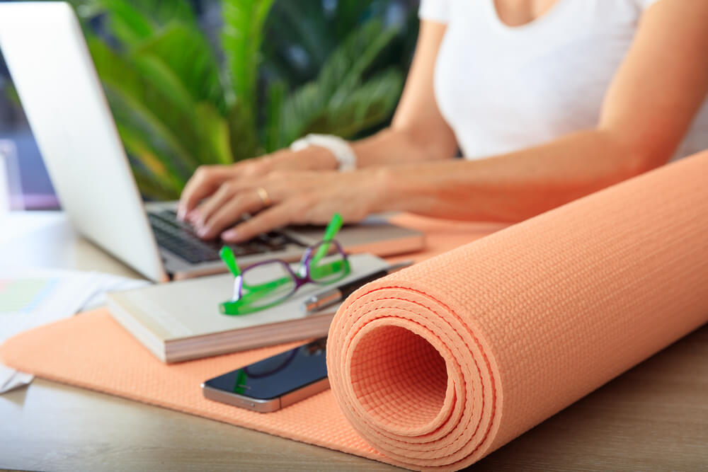 Yoga mat in an office desk with woman working in the background