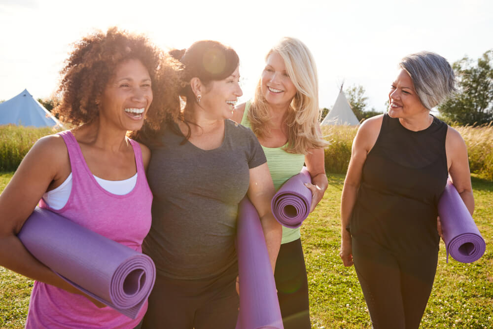 group of mature women in park taking yoga with whole life insurance