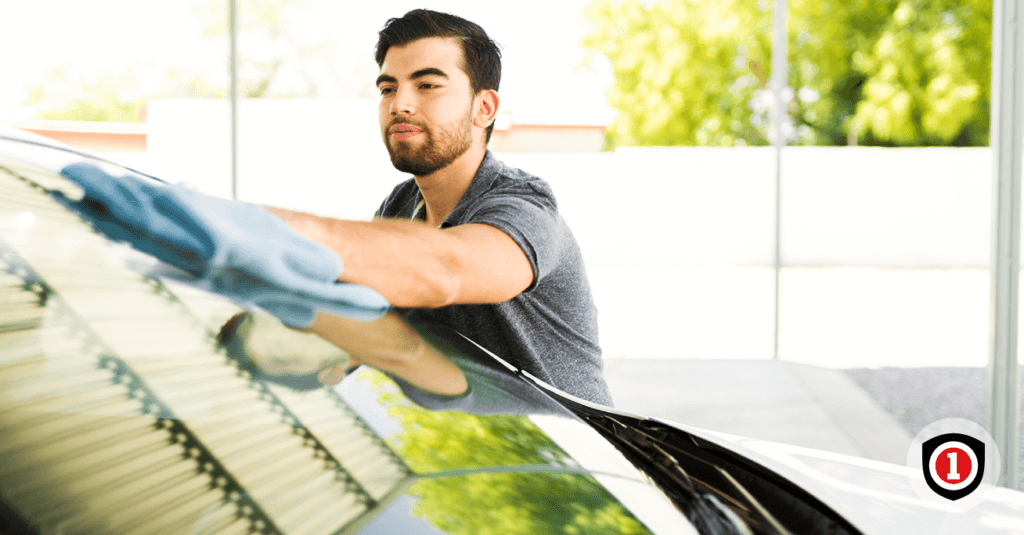 A Hispanic man smiling while cleaning his auto