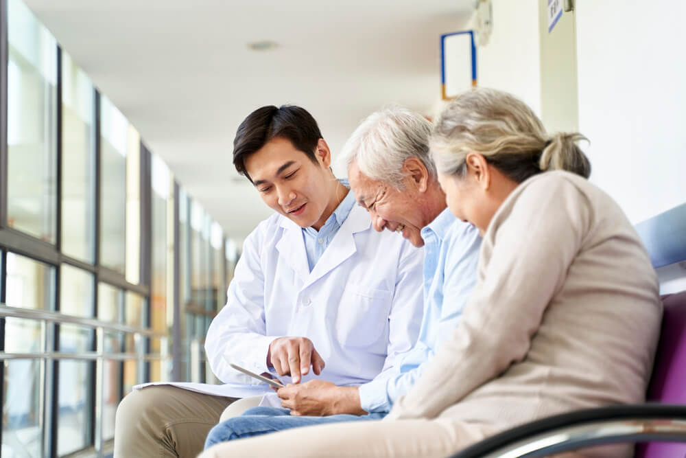 Young,Asian,Doctor,Discussing,Test,Result,And,Diagnosis,With,Senior young asian doctor discussing chart with elderly couple