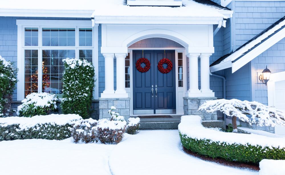 Walkway,To,A,Fresh,Blanket,Of,Snow,On,Residential,Home walkway to home covered in snow with holiday wreaths on front doors
