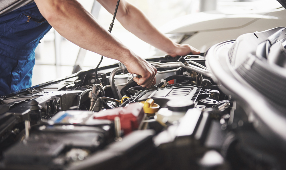 mechanic working under hood of car