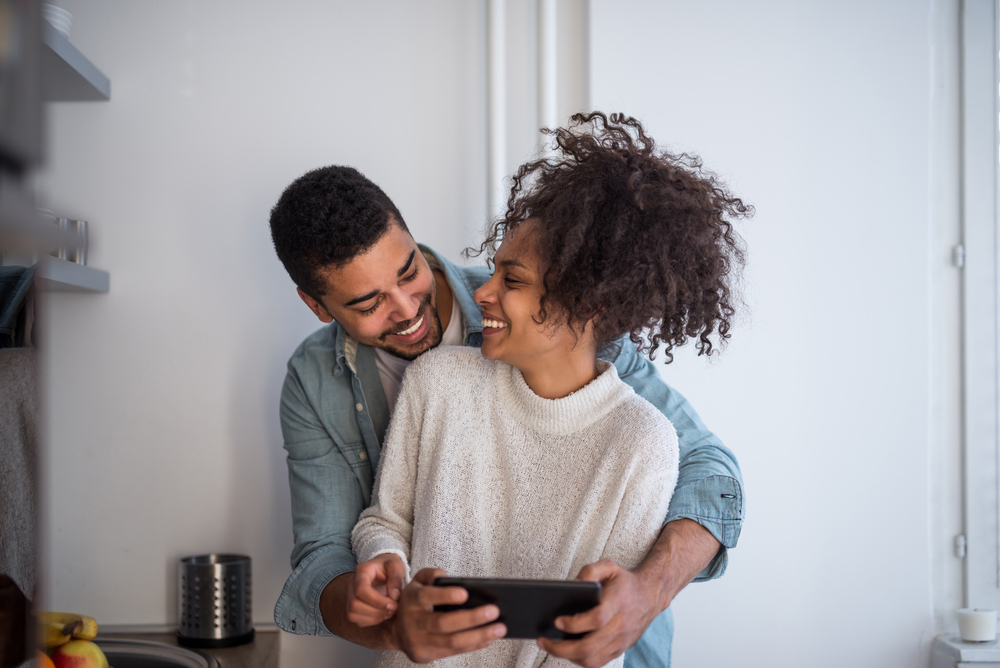Happy,African,American,Couple,Using,A,Tablet,In,The,Kitchen. young married couple embracing
