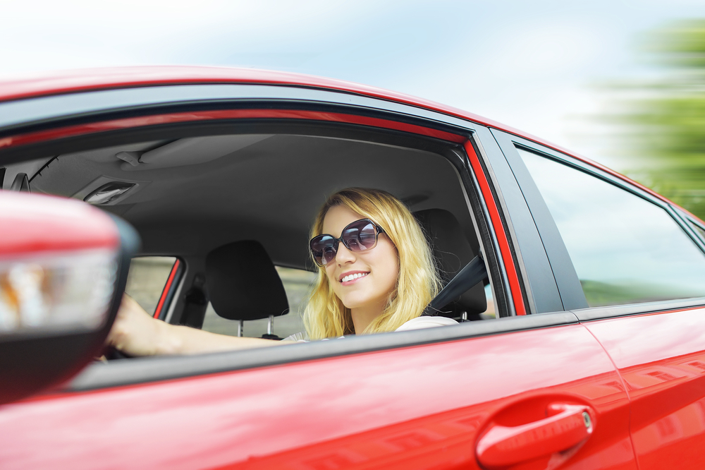 woman driving red car smiling