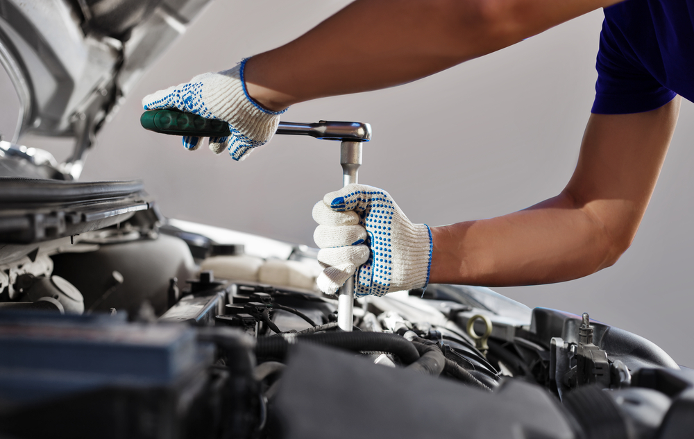 mechanic working under hood of vehicle