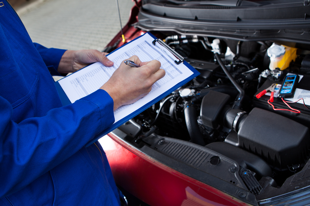 Midsection,Of,Mechanic,Holding,Clipboard,In,Front,Of,Open,Car mechanic going over checklist in front of car