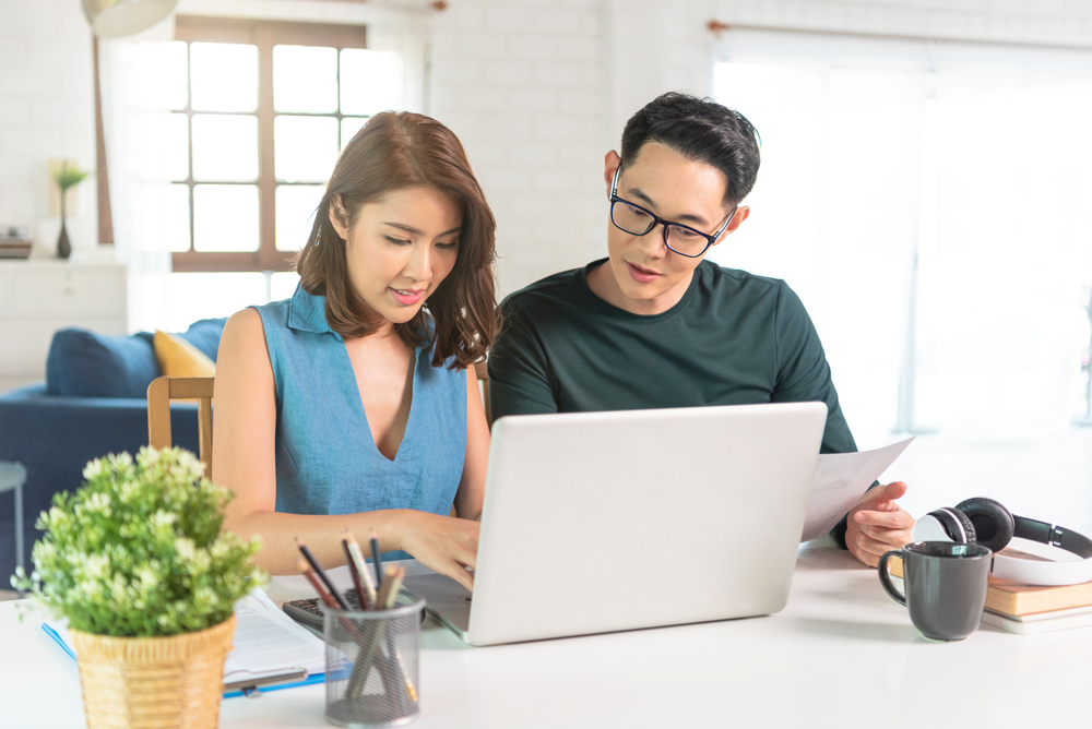 young asian couple sitting at computer researching life insurance