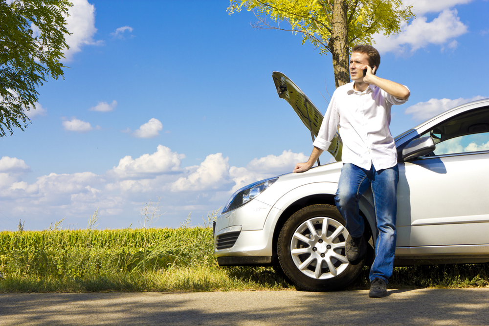 man on phone stranded next to car