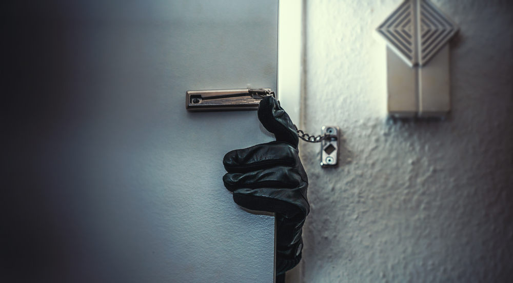 burglar opening apartment door with gloves on