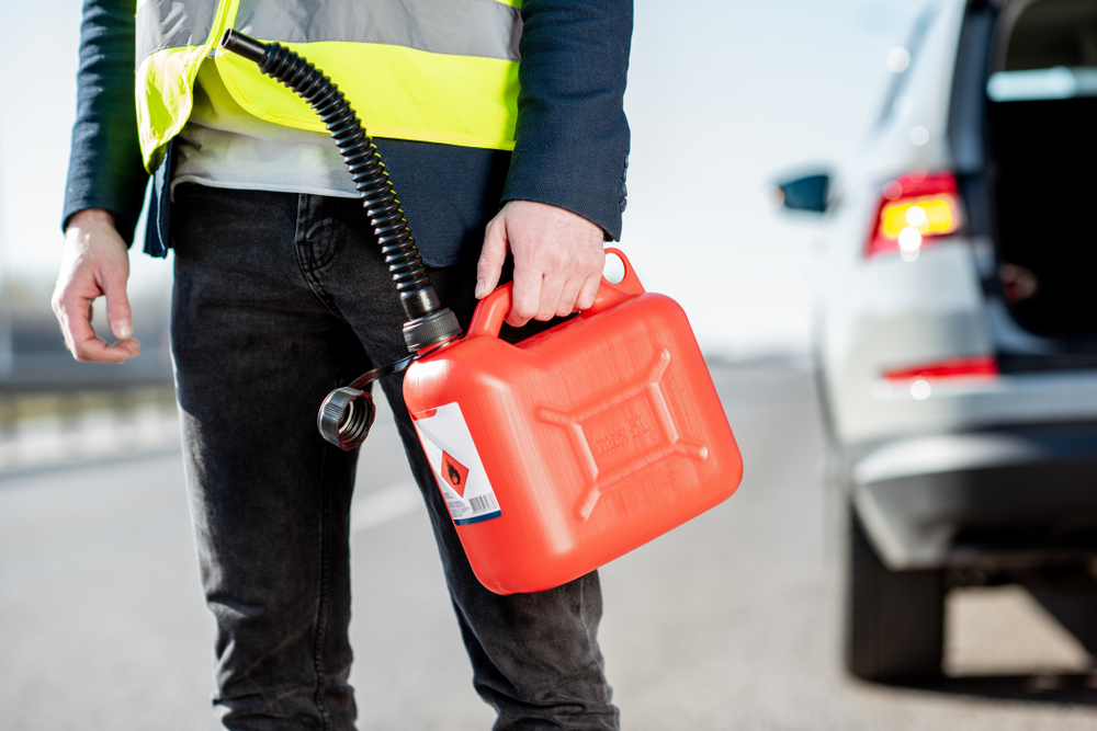 man carrying fuel to car on side of road