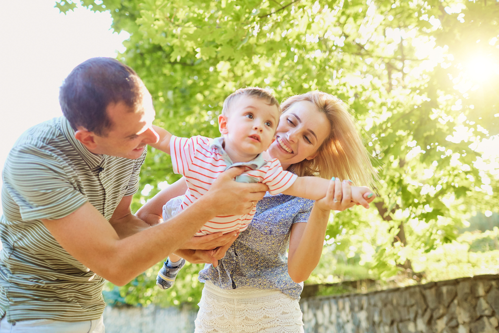 Mother,Father,And,Child,Playing,Flying,In,A,Plane,In Mother father and child playing flying in a plane in summer park