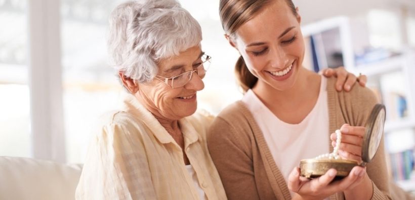 Older woman and younger woman look at a pearl necklace together, showing why valuable items home insurance may not fully cover may need extra protection.