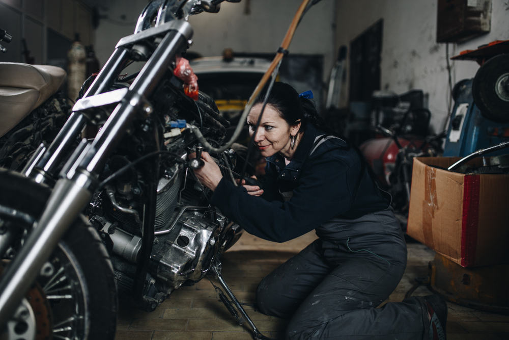 Woman performs maintenance on her motorcycle