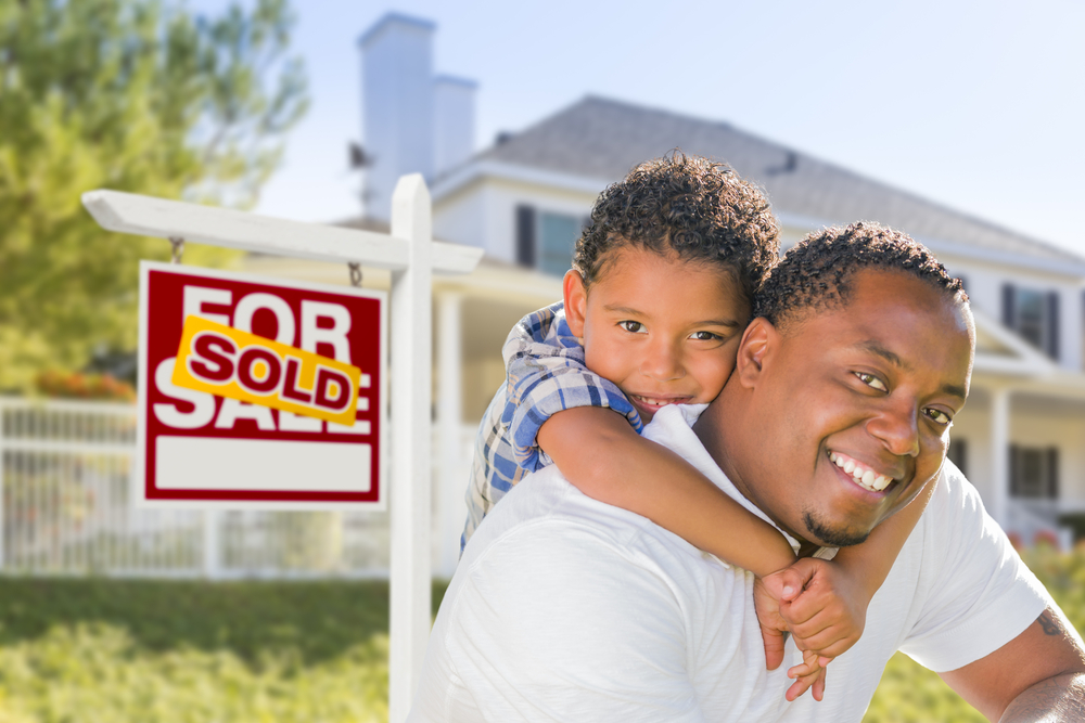 African,American,Father,And,Mixed,Race,Son,In,Front,Of African-American father and son in front of for sale sign with sold sign