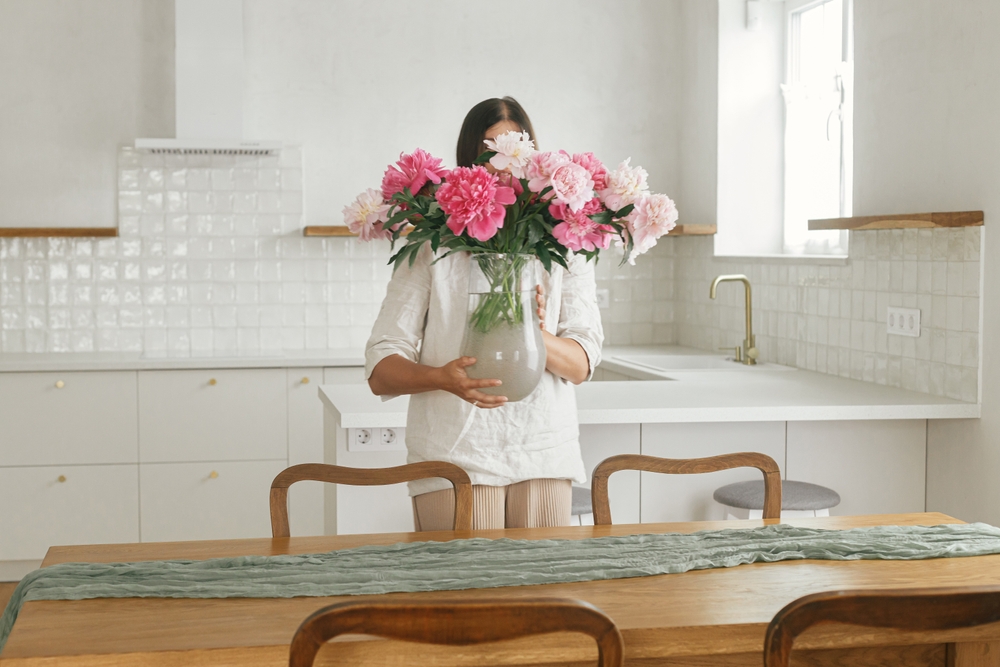 Lady puts fresh flowers on table to stage home