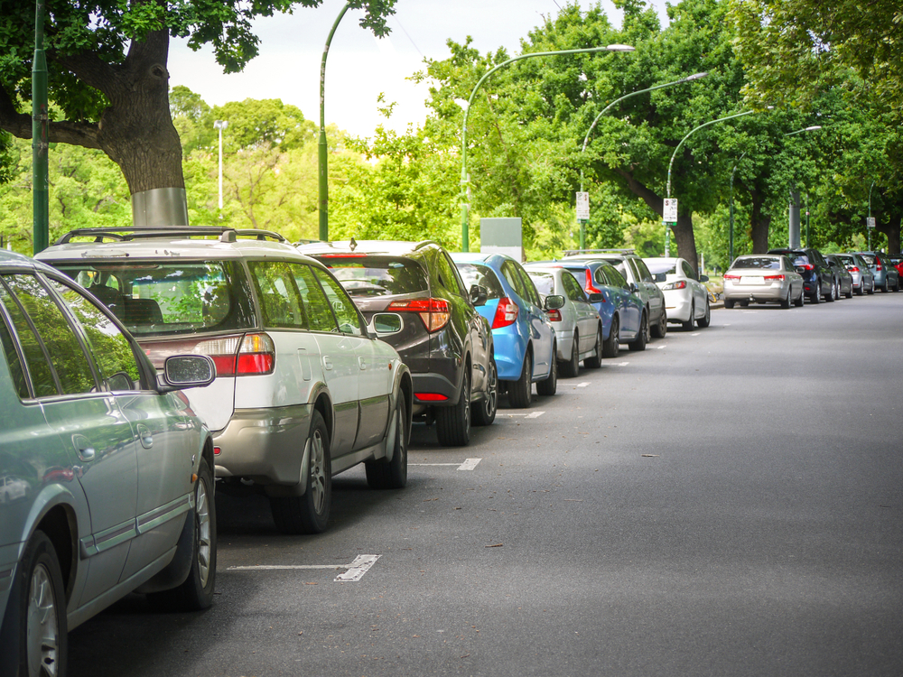 Cars parked in a line on a shady street