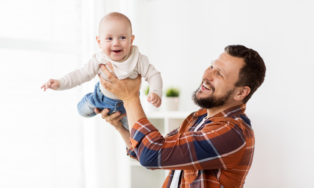 Father playing airplane with his baby son