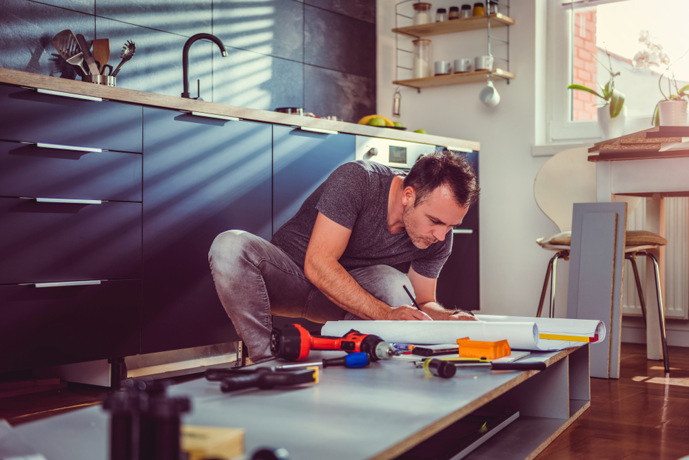 Man working on blueprint to renovate kitchen