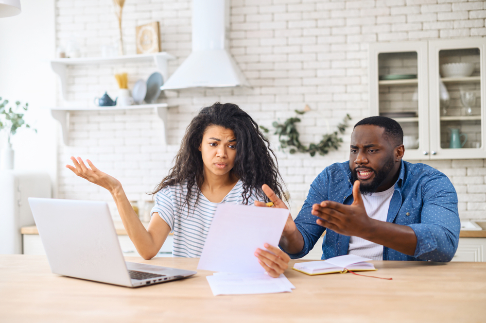 Couple frowns at paperwork confused