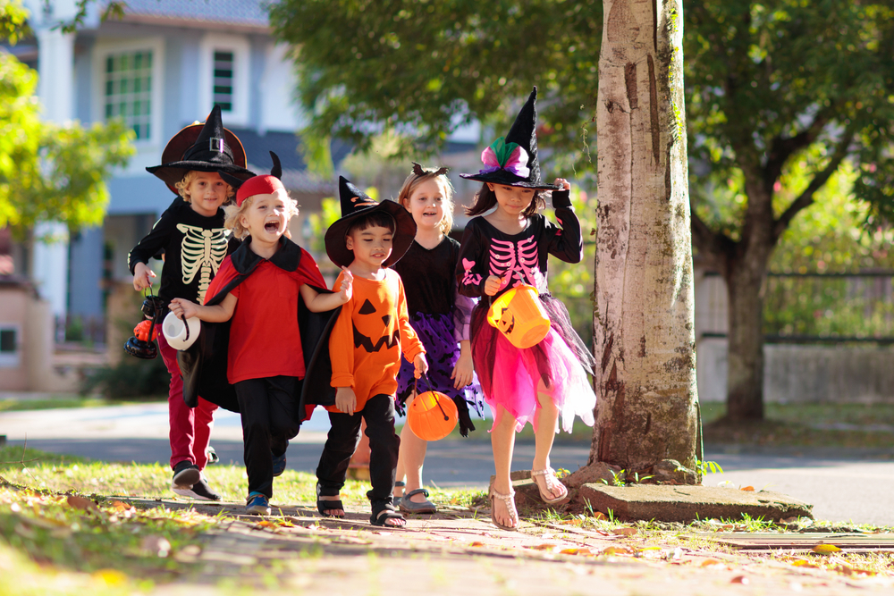 Group of costumed kids go trick or treating.