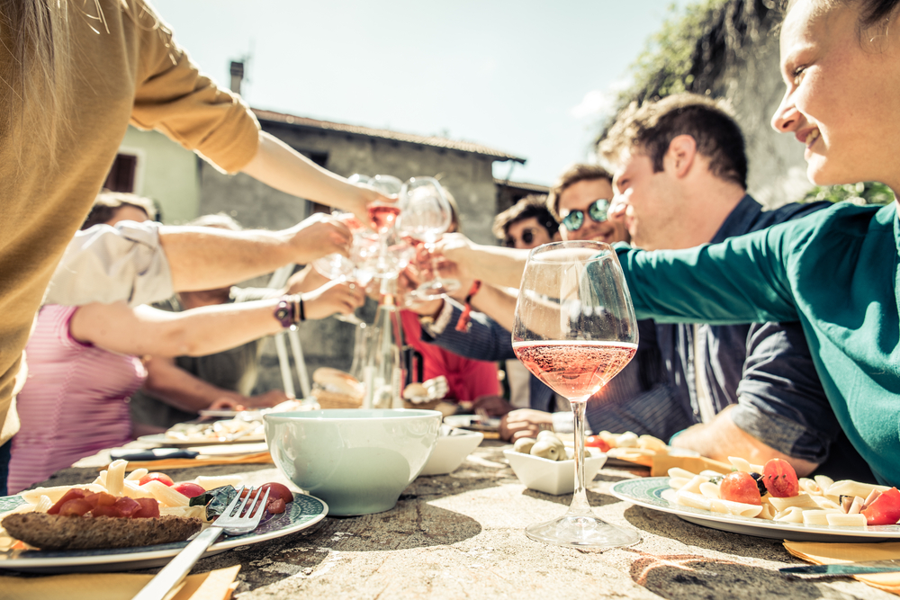 Group of friends and family toasting with wine glasses over holiday meal outside - home insurance liability