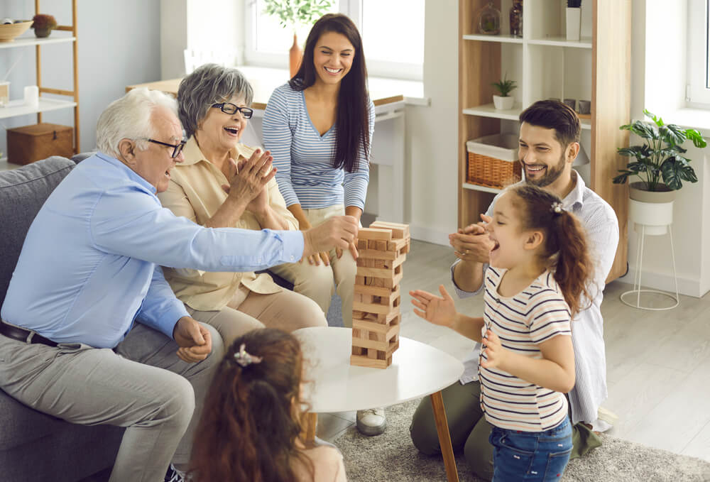 Multi-generational family playing Jenga, life insurance concept.
