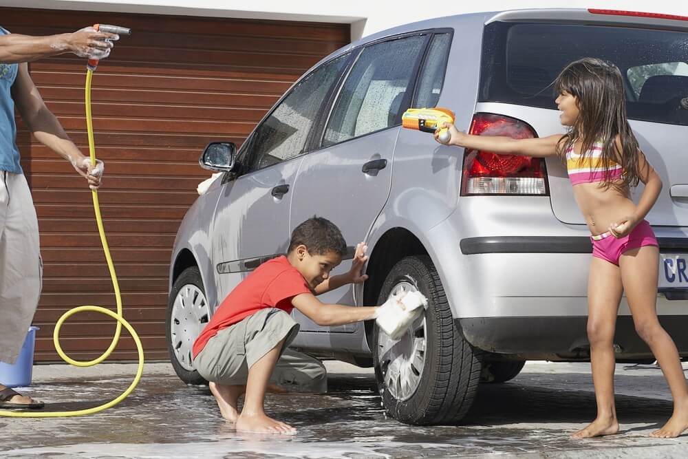 A family washes the family car outside their home.