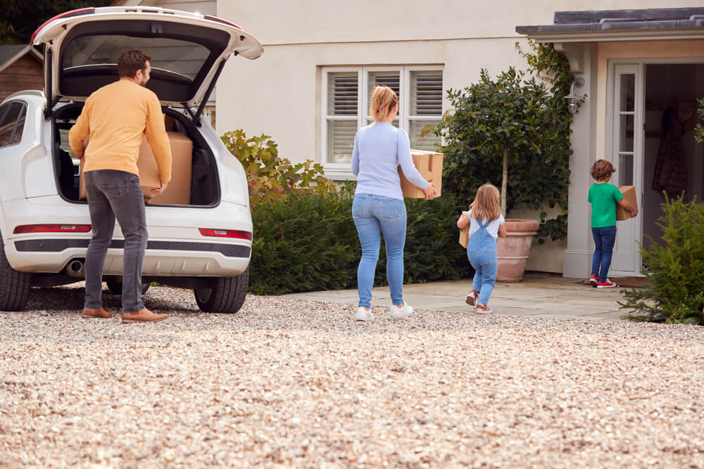 Young family unloading boxes into their new home - concept of saving money by bundling home and car insurance.