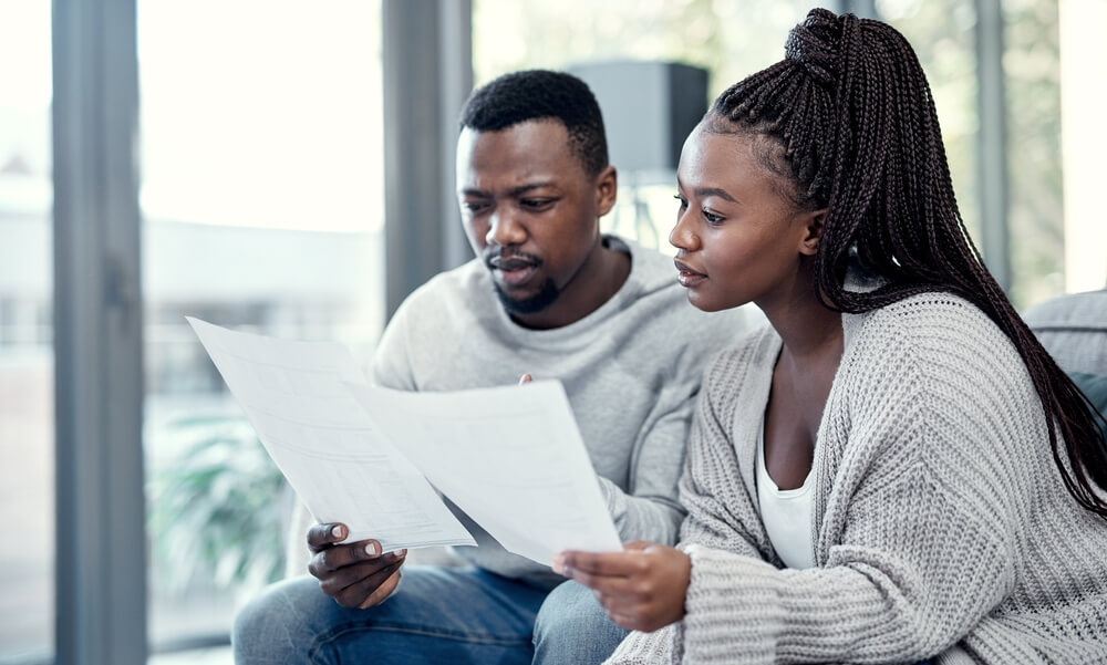 Couple reviewing bills and paperwork at home, illustrating how credit score impacts car insurance rates when budgeting for coverage.