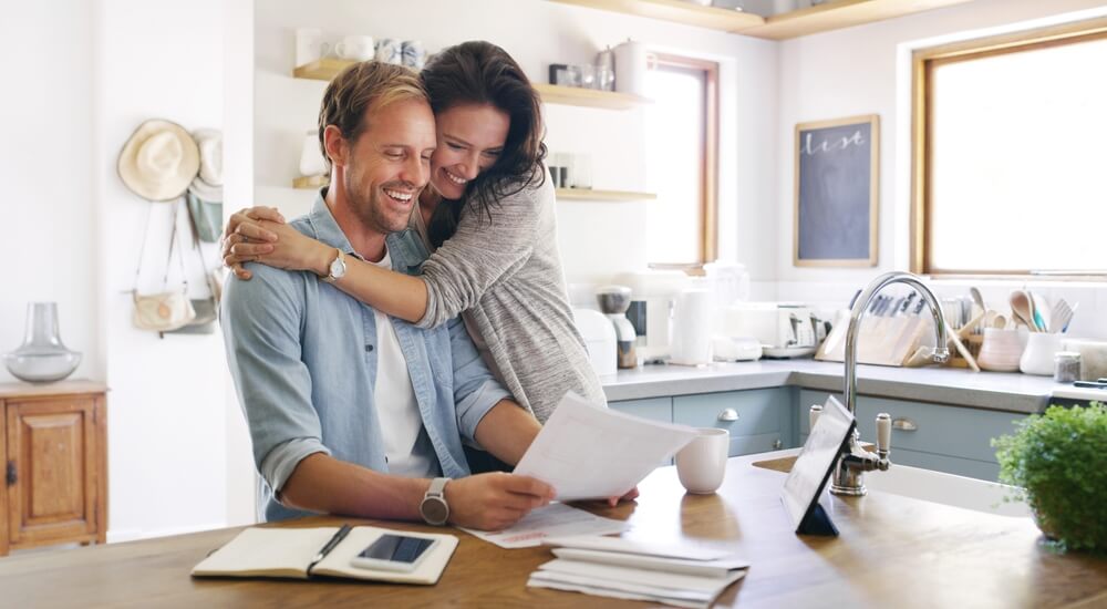 Couple reviewing paperwork and bills together at a kitchen table, showing how credit score impacts car insurance rates.