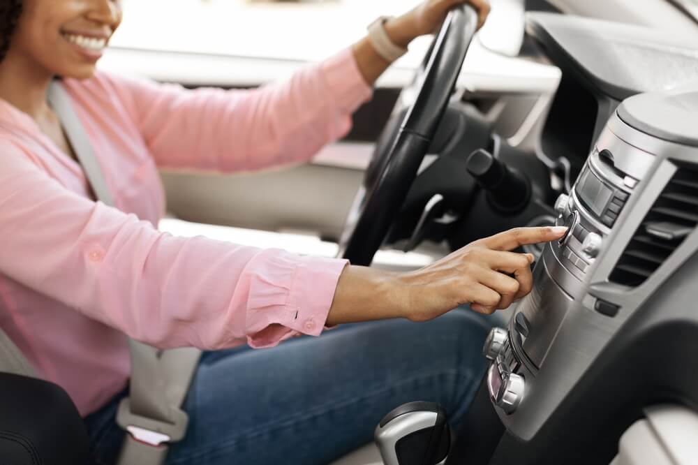 Woman fiddles with her dashboard and radio controls - best car insurance.