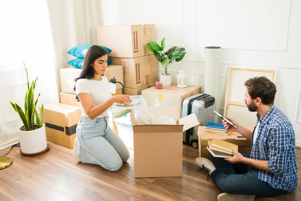 Couple unpacking moving boxes illustrating factors that can affect renters insurance rates.